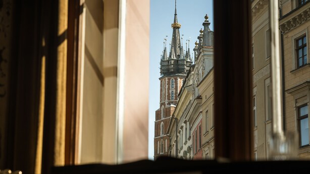 Vista a través de una ventana que muestra un edificio con arquitectura ornamentada y una aguja.