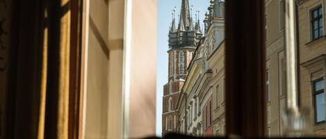A view through a window with a building featuring ornate architecture and a spire.