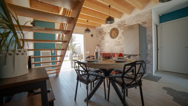 Un comedor con una mesa de madera, sillas y un reloj en la pared.