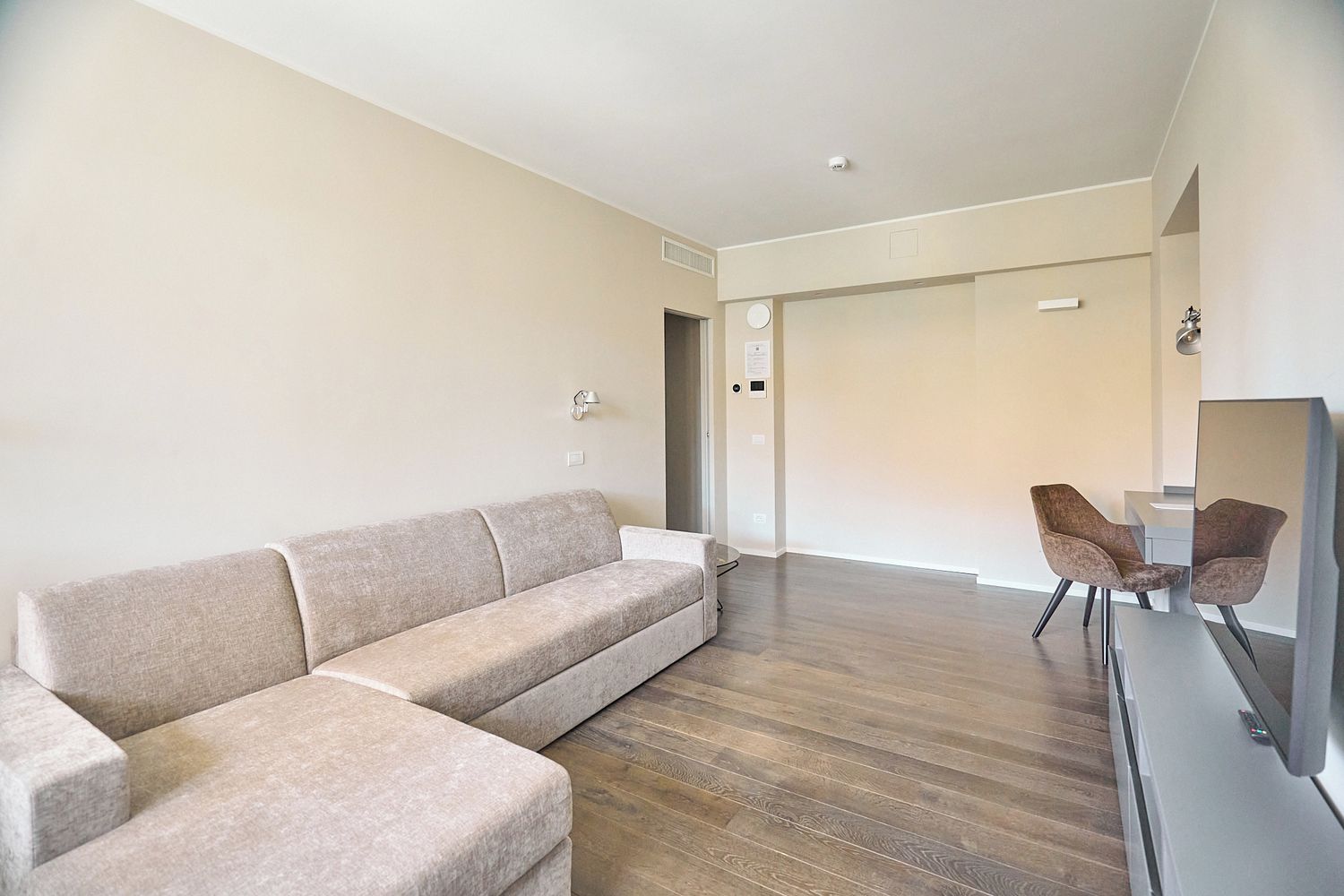 A modern living room with a sofa, a chair, and a flat-screen TV.