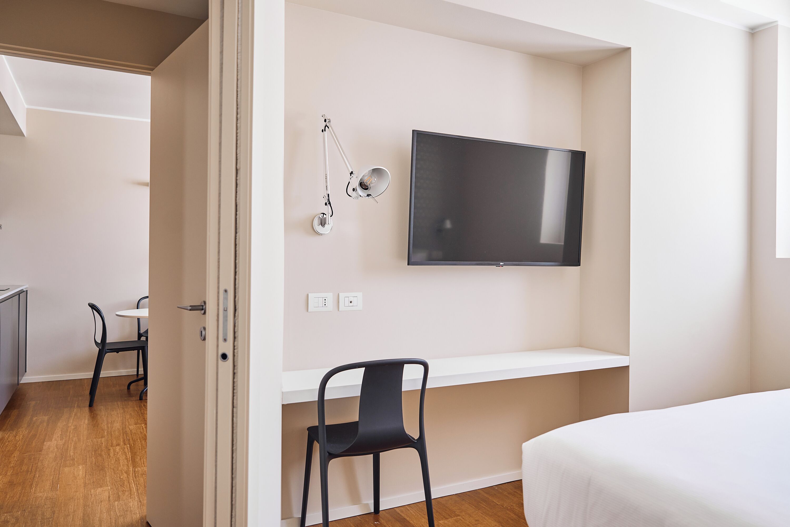 Una habitación de hotel moderna con una televisión de pantalla plana, un escritorio con una silla y una cama.