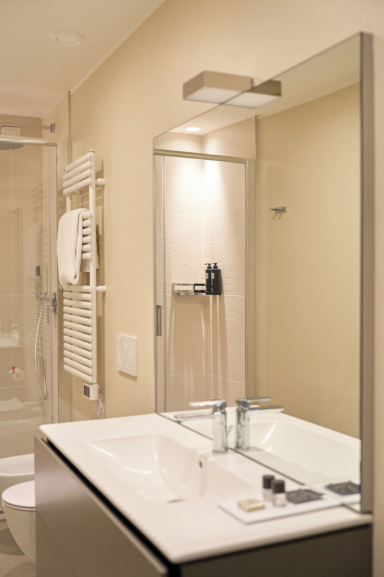 A modern bathroom with a glass-enclosed shower, a white sink with a mirror, and a towel rack.