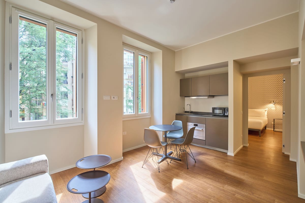 Un espacio habitable compacto con comedor, kitchenette y un dormitorio con pared estampada.
