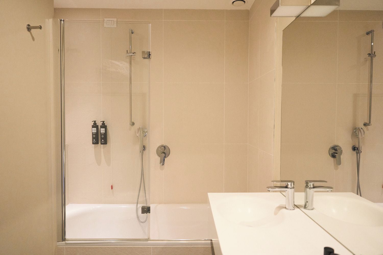 Un baño con ducha envuelta en vidrio, una bañera blanca y un tocador con espejo.