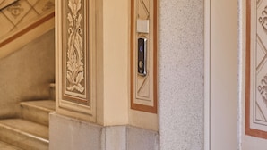 A corner of a building with a textured wall, a door, and a decorative mold trim. - Ariosto Living (Milan)
