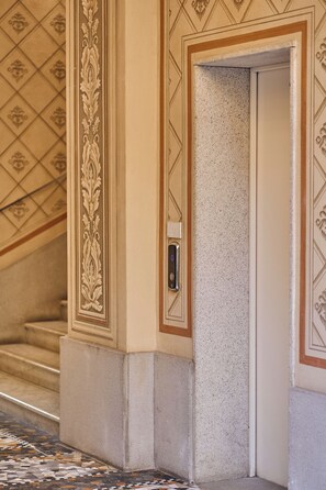 A corner of a building with a textured wall, a door, and a decorative mold trim. - Ariosto Living (Milan)