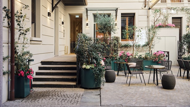 A courtyard with outdoor seating, a staircase, and potted plants. - Ariosto Living (Milan)