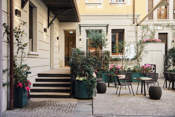 A courtyard with outdoor seating, a staircase, and potted plants.
