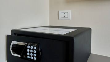 Eine schwarze Mikrowelle steht auf einer Arbeitsplatte, mit einer digitalen Tastenanzeige, einer Steckdose und einem an der Wand montierten Fernseher darüber.
