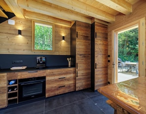 Een moderne keuken met houten kastjes, een inbouwoven en een groot raam.