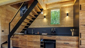 Eine Küche mit Holzvertäfelung, einer schwarzen Treppe und einem Fenster mit Blick auf Bäume.