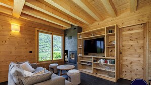 Ein Holzinnenraum mit einer Couch, einem Fernseher, einem Kamin und Regalen.