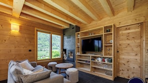 Un intérieur en bois avec un canapé, une télévision, une cheminée et des étagères.