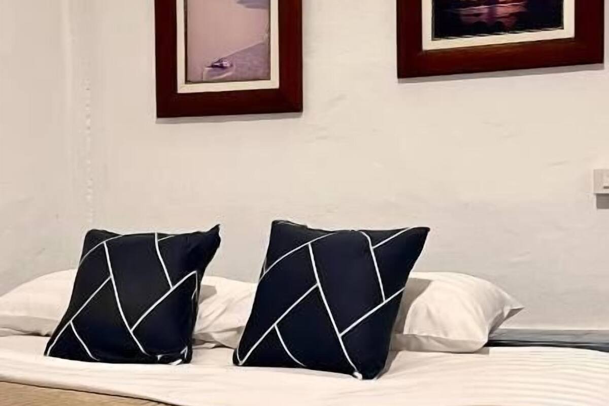 Ein Hotelzimmer mit einem Bett, zwei gerahmten Bildern an der Wand und einer braunen, strukturierten Decke.