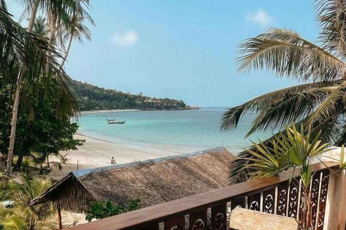 Ein Holztisch mit zwei Gläsern mit Getränken, eine Bank und Blick auf Strand und Meer.