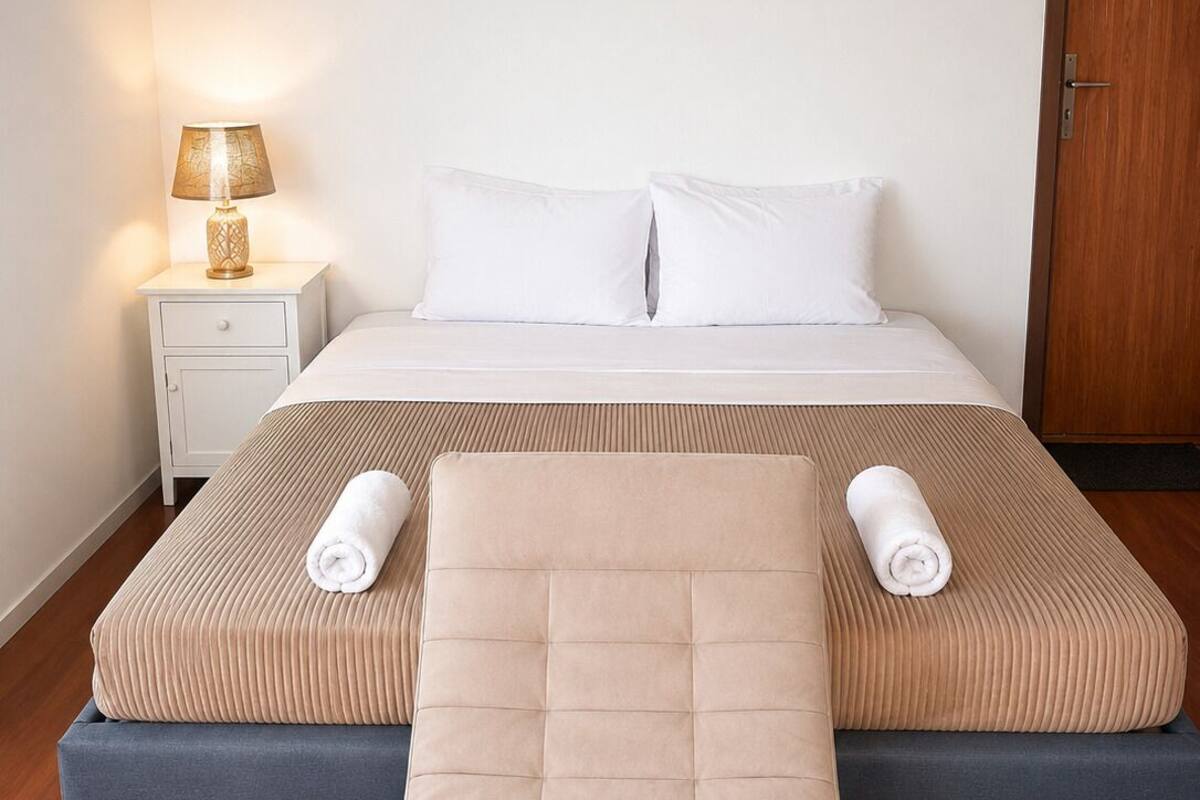 Ein Hotelzimmer mit Bett, Nachttisch, Lampe und Klimaanlage.