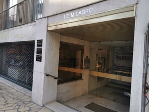 Ein Gebäudeeingang mit einem Schild, auf dem 'LE MILAGRO' steht, und eine sichtbare Schaufensterfront mit Glasfassade.