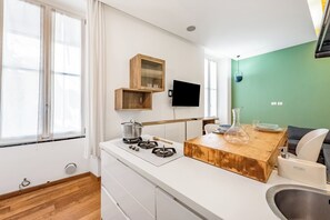 Una cocina moderna con encimera de madera, estufa integrada, fregadero y televisor montado en la pared.