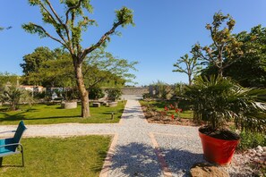 Un sentier de jardin menant à un banc, entouré d’arbres et de plantes en pot.