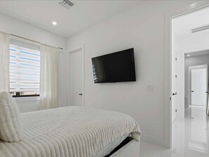 A bedroom with a bed, a television mounted on the wall, and a door. - 4BR Marco Island home with heated pool, WiFi, and full kitchen. (Marco Island)