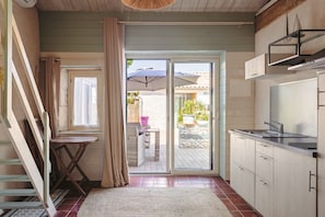 Une cuisine avec une porte-fenêtre coulissante donnant sur un espace extérieur, une petite table avec une chaise et un escalier.