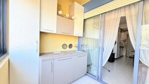 Una cucina con armadi, un piano di lavoro e una porta scorrevole in vetro che dà su un balcone.