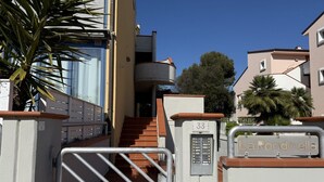Un cancello conduce a un edificio residenziale con una scala che porta a un piano superiore.