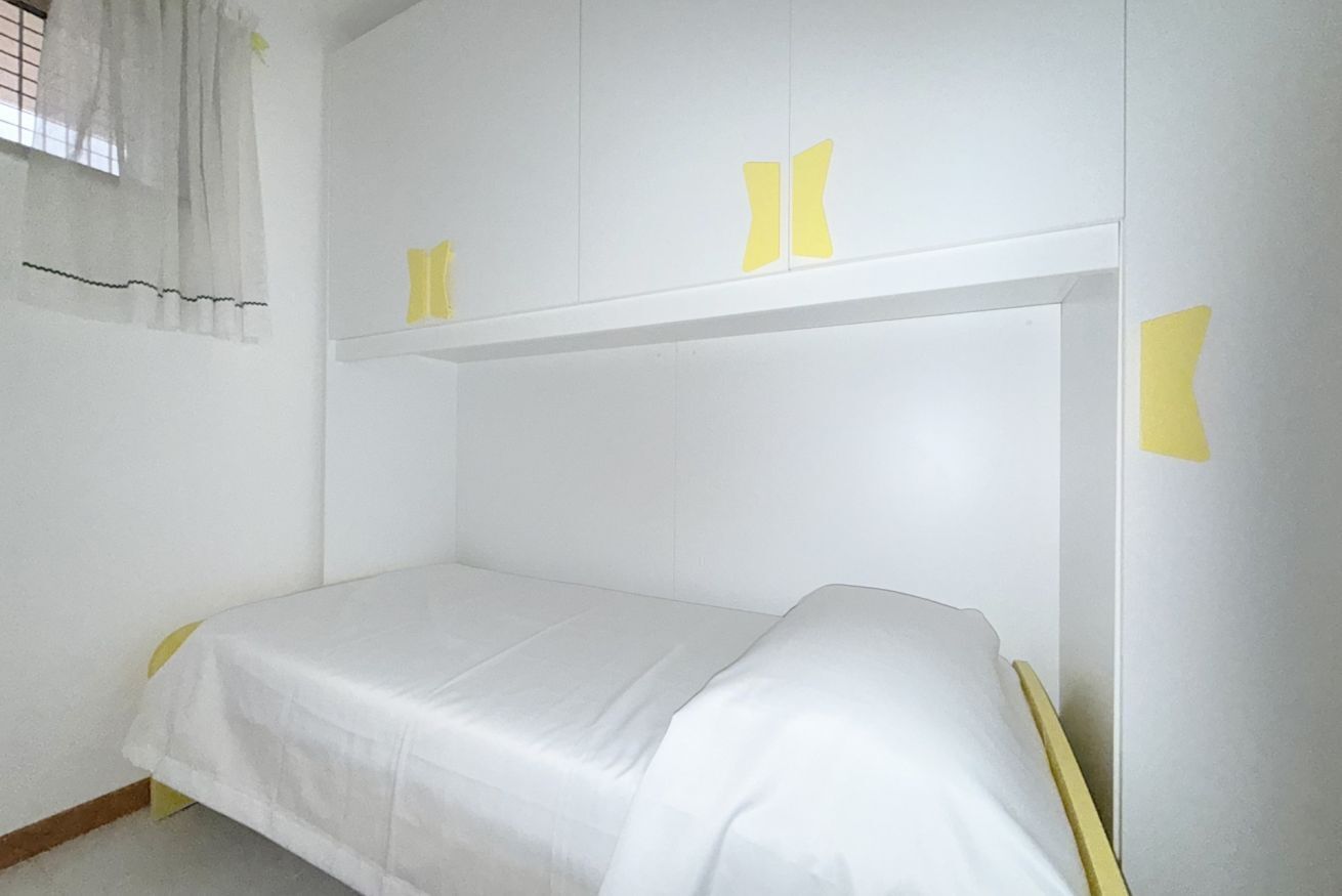 A single bed with a white mattress and a headboard with yellow accents.