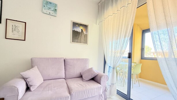 Un soggiorno con un divano, un quadro incorniciato e un orologio appeso al muro.