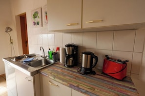 A kitchen with a striped countertop, a coffee maker, a kettle, and a toaster.