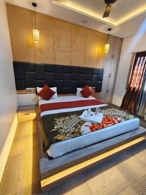 A modern hotel room with a large bed, a headboard, bedside tables, and a ceiling fan. - The Kashi Iconic Guest House (Varanasi)