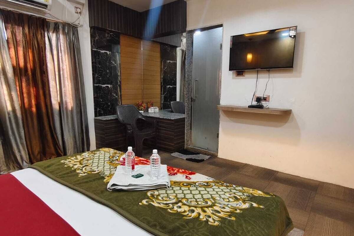 Una habitación de hotel con una cama, un escritorio, un televisor y aire acondicionado.