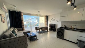 A modern living room with a sofa, dining table, and kitchen area including a washing machine. - Fouka North Coast CL3-CH19-02 (Marsa Matrouh)