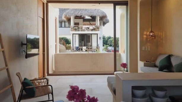 A modern interior with a balcony, a sofa, a TV, and a hanging light fixture. - Apartment 1 Boutique in La Punta *Starlink | Swimming Pool*. (La Barra de Colotepec)
