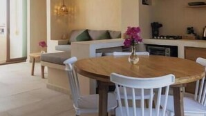 A dining area with a round wooden table, white chairs, and a vase with flowers. - Apartment 1 Boutique in La Punta *Starlink | Swimming Pool*. (La Barra de Colotepec)