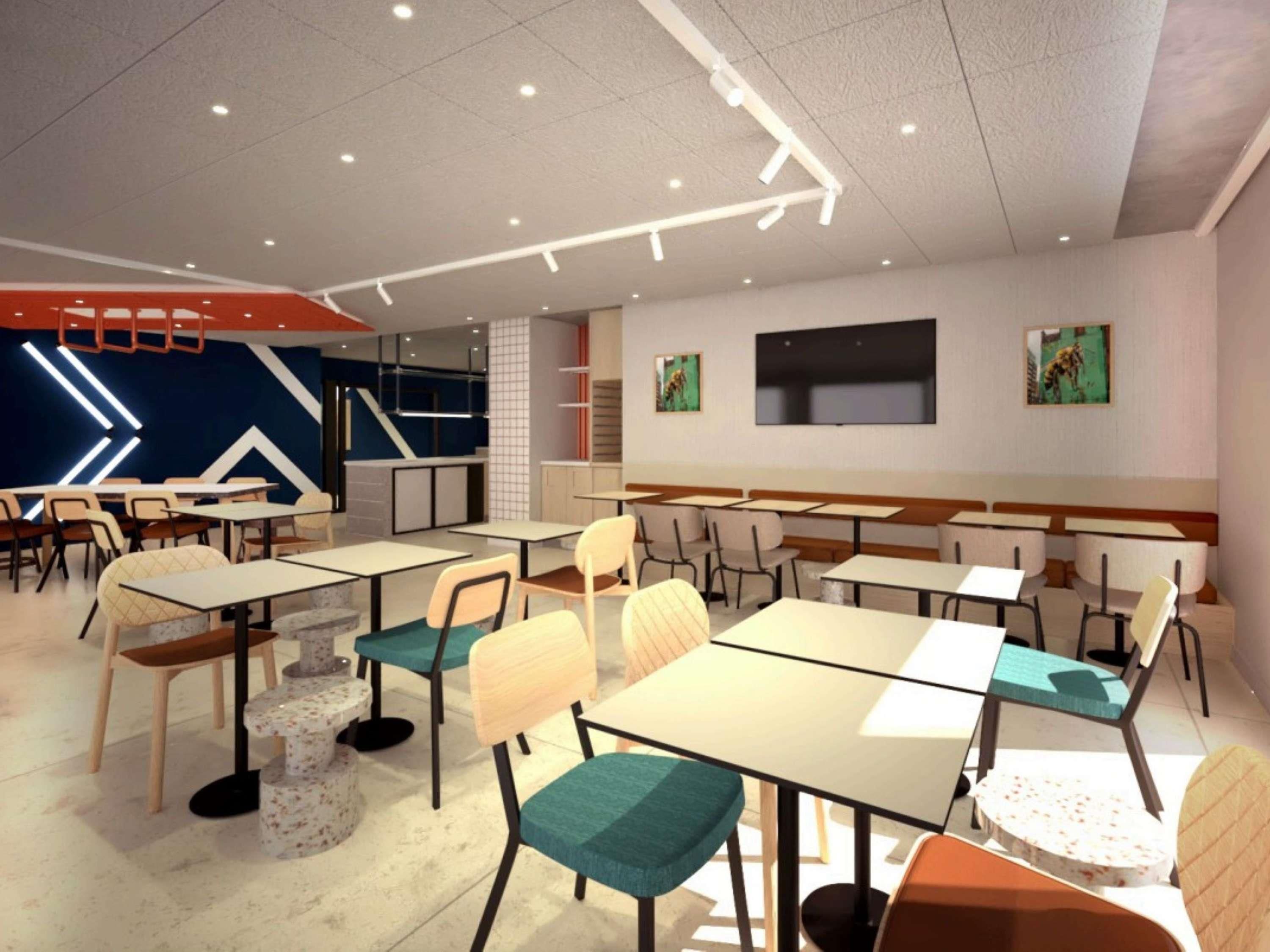 Een moderne eethoek met meerdere tafels en stoelen, een flatscreen televisie aan de wand en een trap naar een hoger gelegen verdieping.