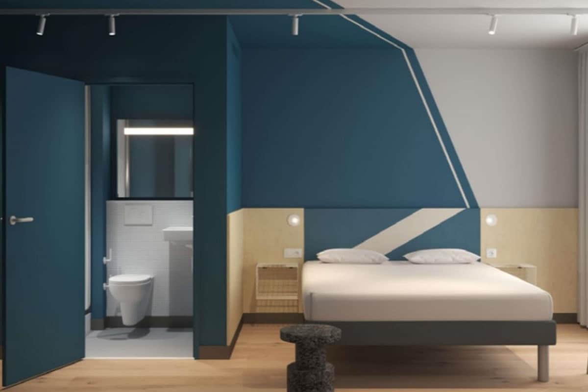 A modern bedroom with a bed, bedside tables, and a bathroom visible through an open door.