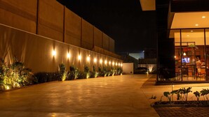 Exterior moderno de un edificio iluminado por la noche, con luces en la pared y un área de entrada con asientos.