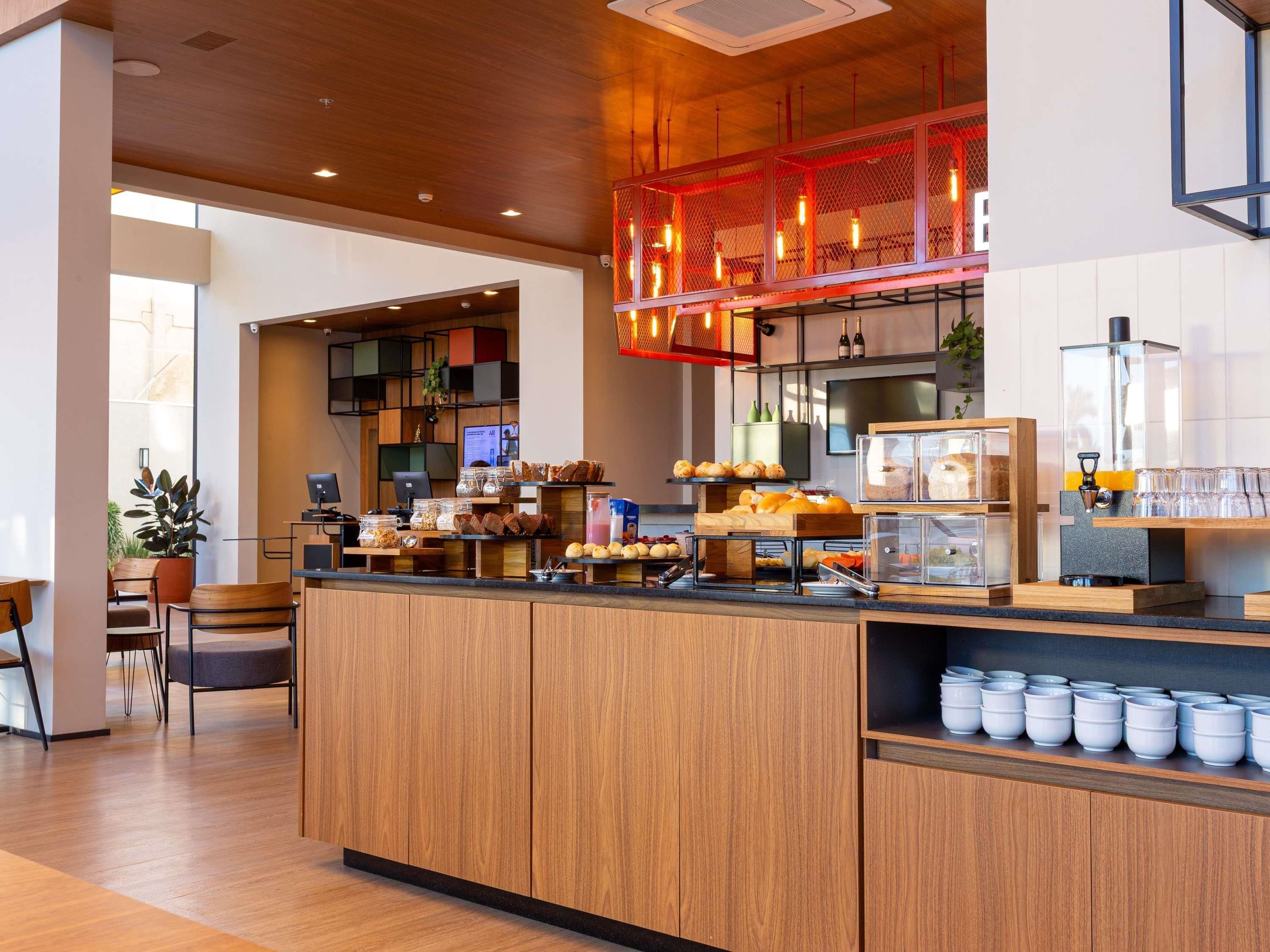 A modern cafe with wooden counters, a coffee machine, and various baked goods.