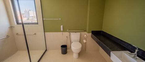 Un baño con inodoro, ducha, lavabo y cubo de basura.