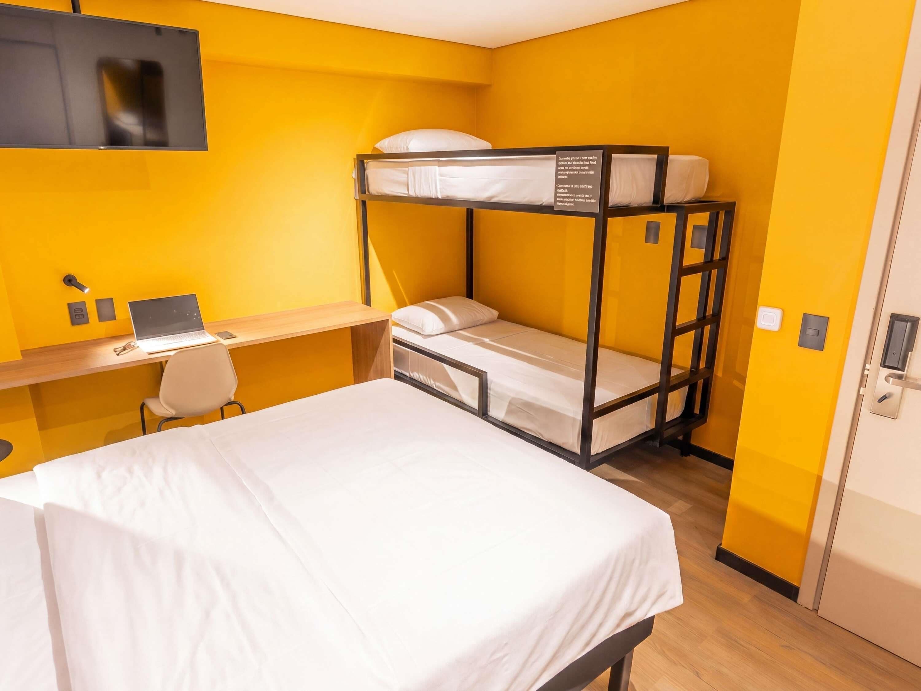 A bunk bed room with a desk, laptop, and chair.