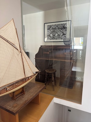 A model sailboat on a wooden table, a dark wooden cabinet, a small stool, and a framed artwork on the wall. - Prime Location mews house - Sleeps 6. Notting Hill Gate / Kensington High St (London)