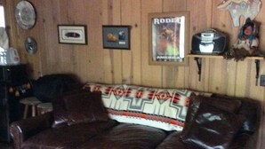 Un canapé en cuir marron agrémenté d’un plaid à motifs, d’une affiche encadrée et d’un objet décoratif posé sur une étagère.