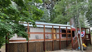 Un chalet rustique avec un toit en métal, une terrasse en bois et un espace clôturé.