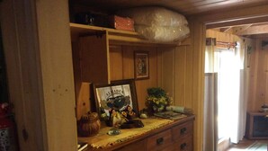 Une commode en bois avec de nombreux tiroirs, un tableau encadré, un vase avec des fleurs et un grand sac en plastique posé sur le dessus.