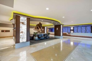 Eine moderne Hotelhalle mit Empfangstresen, Sitzgelegenheiten und dekorativen Wandverkleidungen.