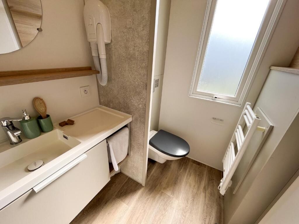 A compact bathroom with a toilet, sink, and towel rack.