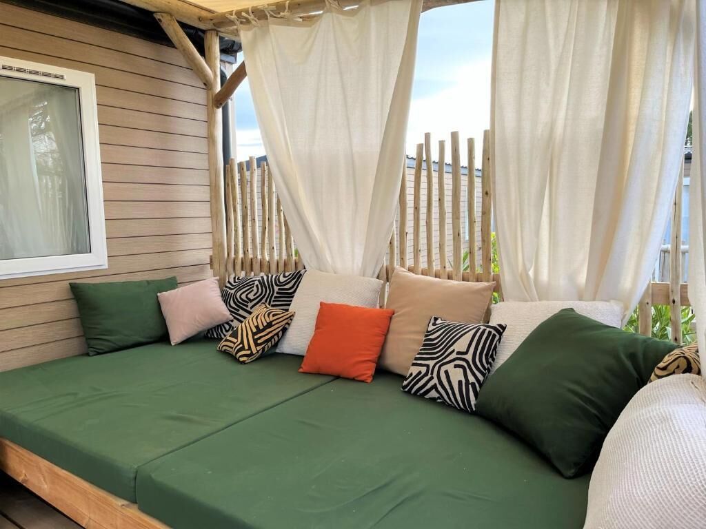 Una terraza de madera con un sofá verde y cojines estampados.