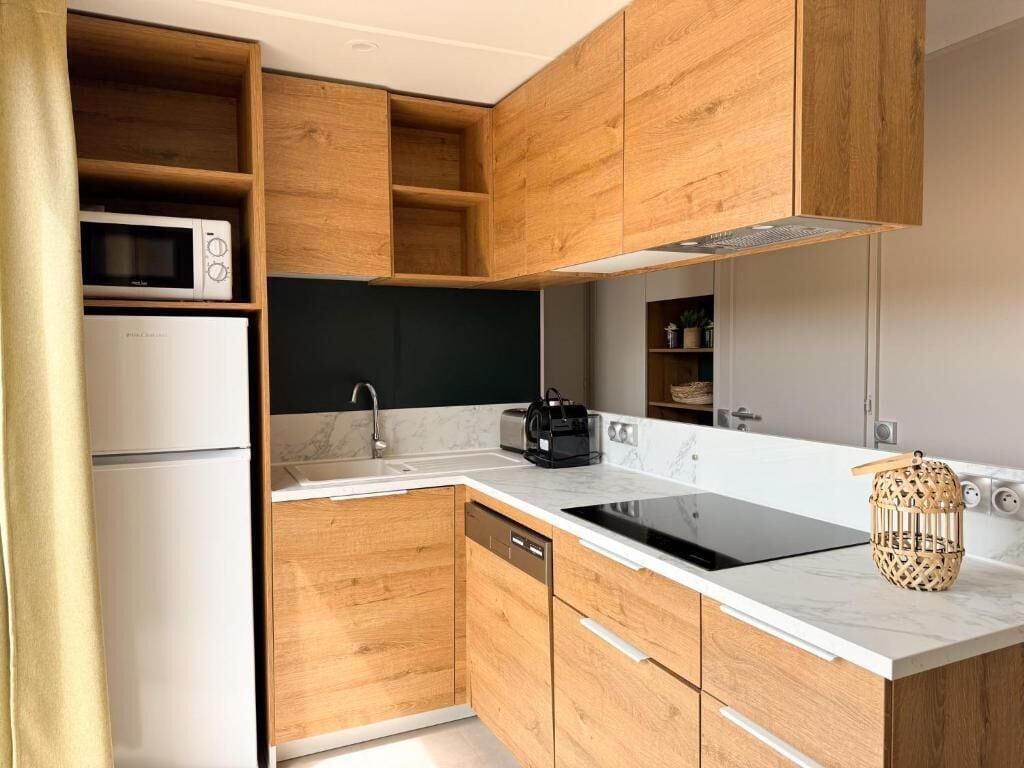 Una cocina moderna con armarios de madera, microondas integrado, lavavajillas y cocina negra.