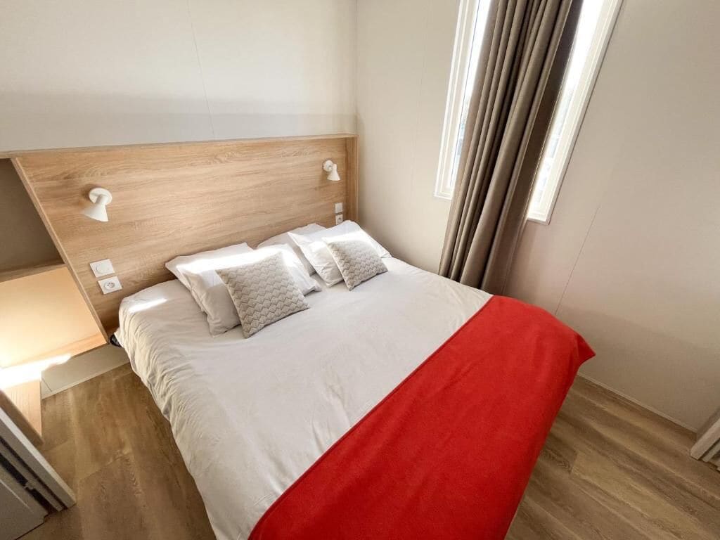 Une chambre d’hôtel avec un lit, une table de chevet, une lampe et une fenêtre avec des rideaux.